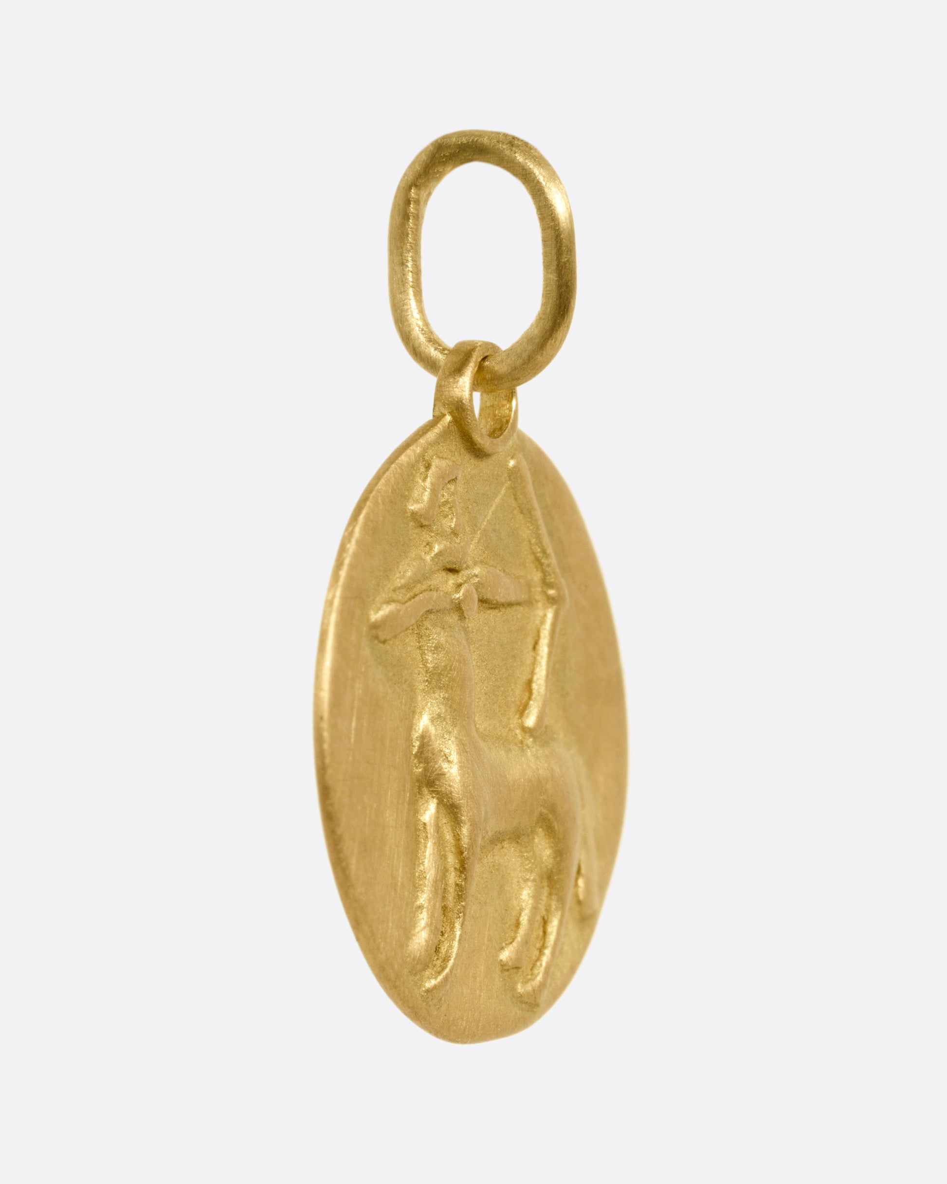 A yellow gold circular Sagittarius pendant with the archer, shown from the side.