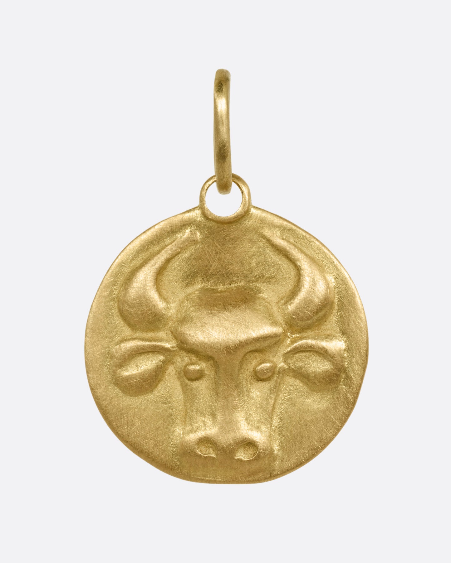 A circular yellow gold Taurus pendant with a bull head, shown from the front.