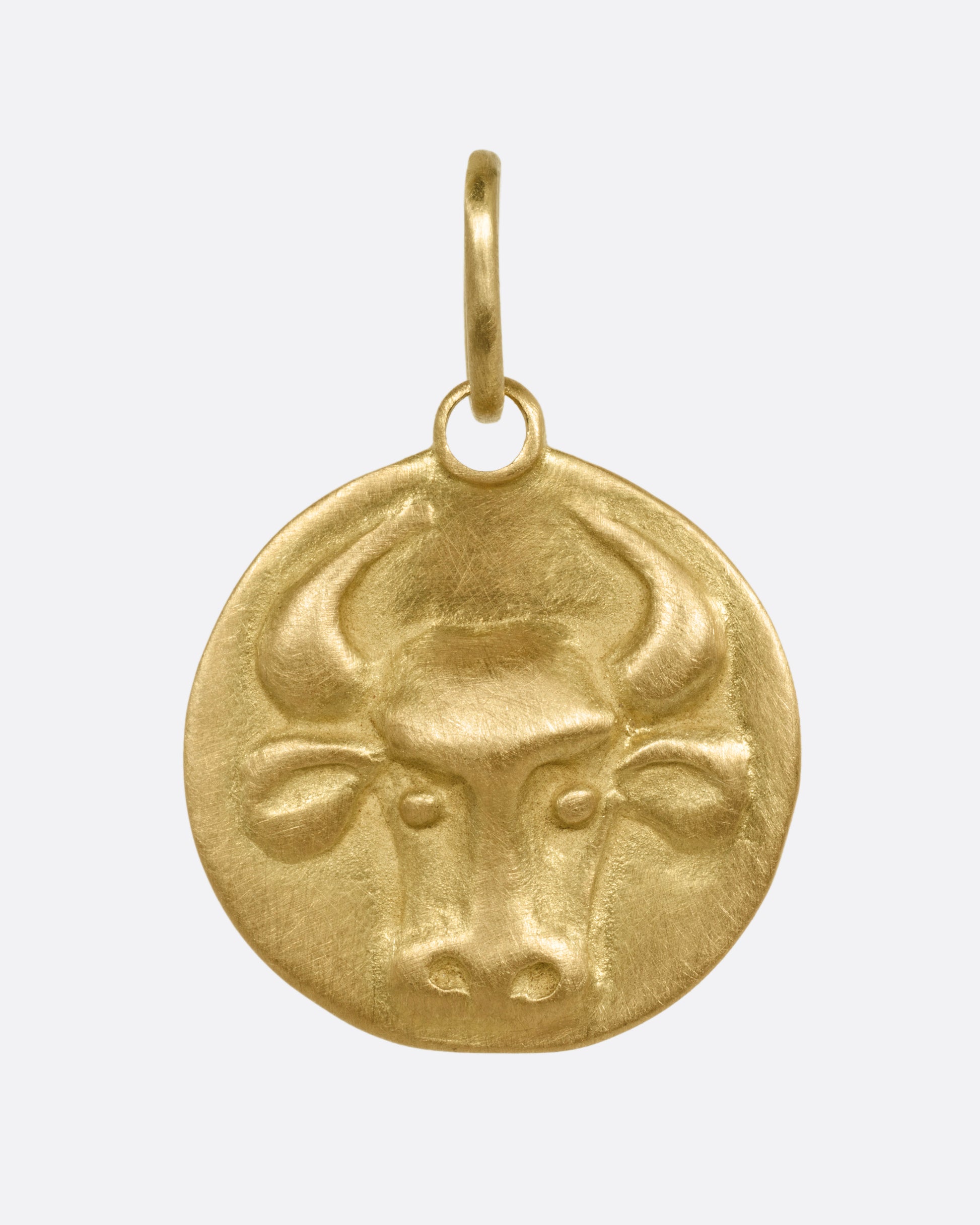 A circular yellow gold Taurus pendant with a bull head, shown from the front.