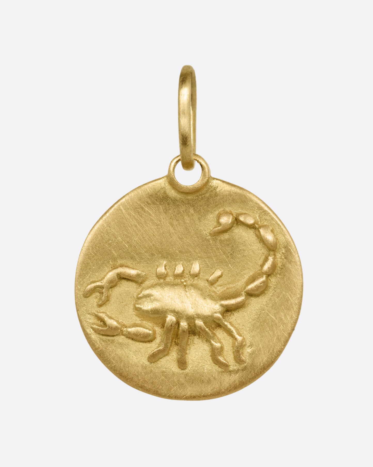 A circular yellow gold Scorpio pendant with a scorpion on its front, shown from the front.