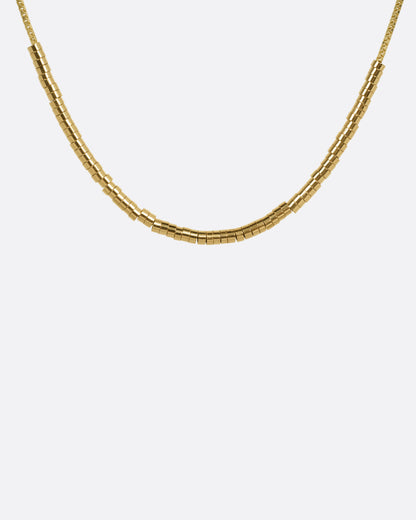 A yellow gold chain necklace with a queue of cylindrical gold beads, shown from the front.