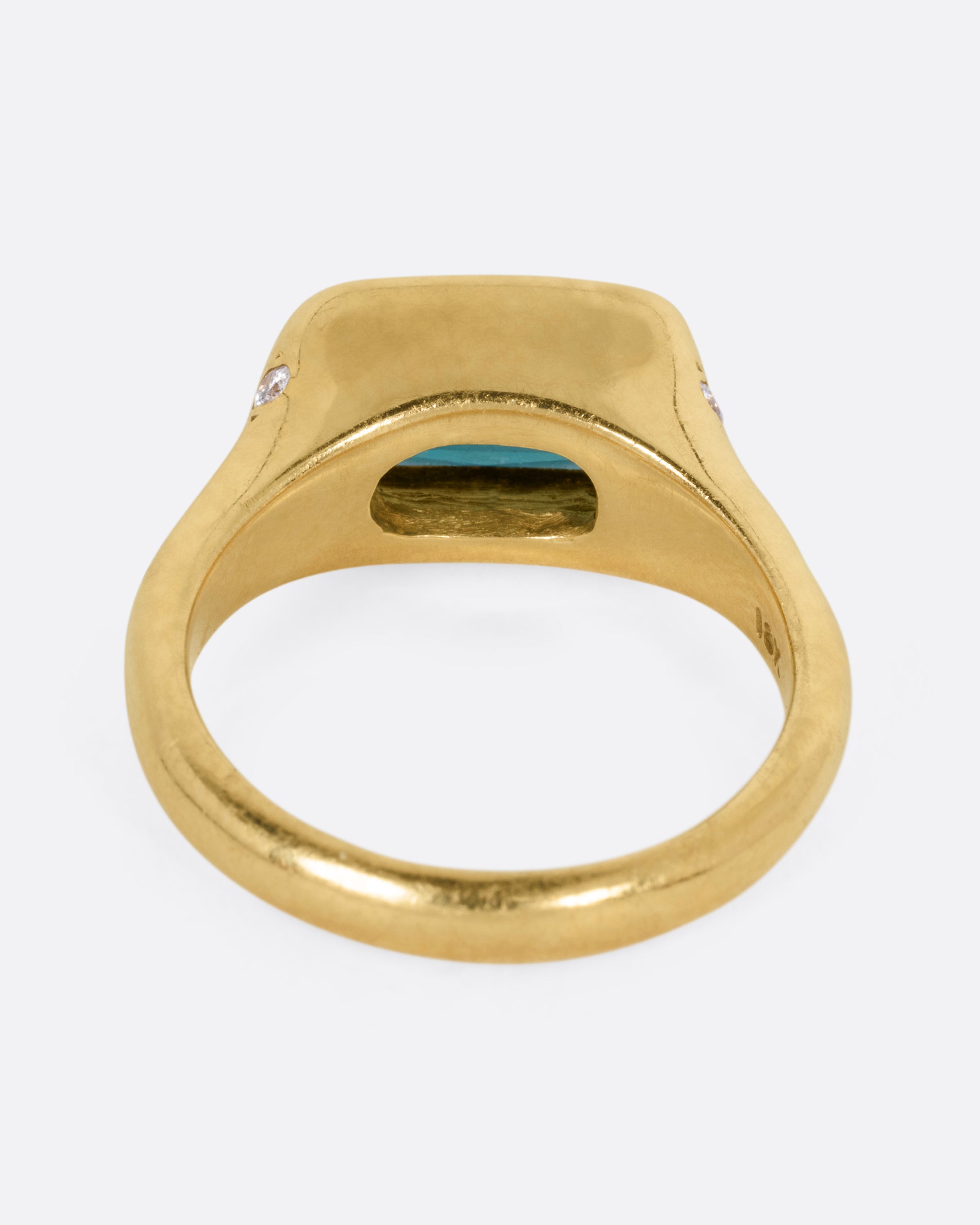 A yellow gold ring with a rectangular green tourmaline at the center and diamonds on either shoulder. Shown from the back.