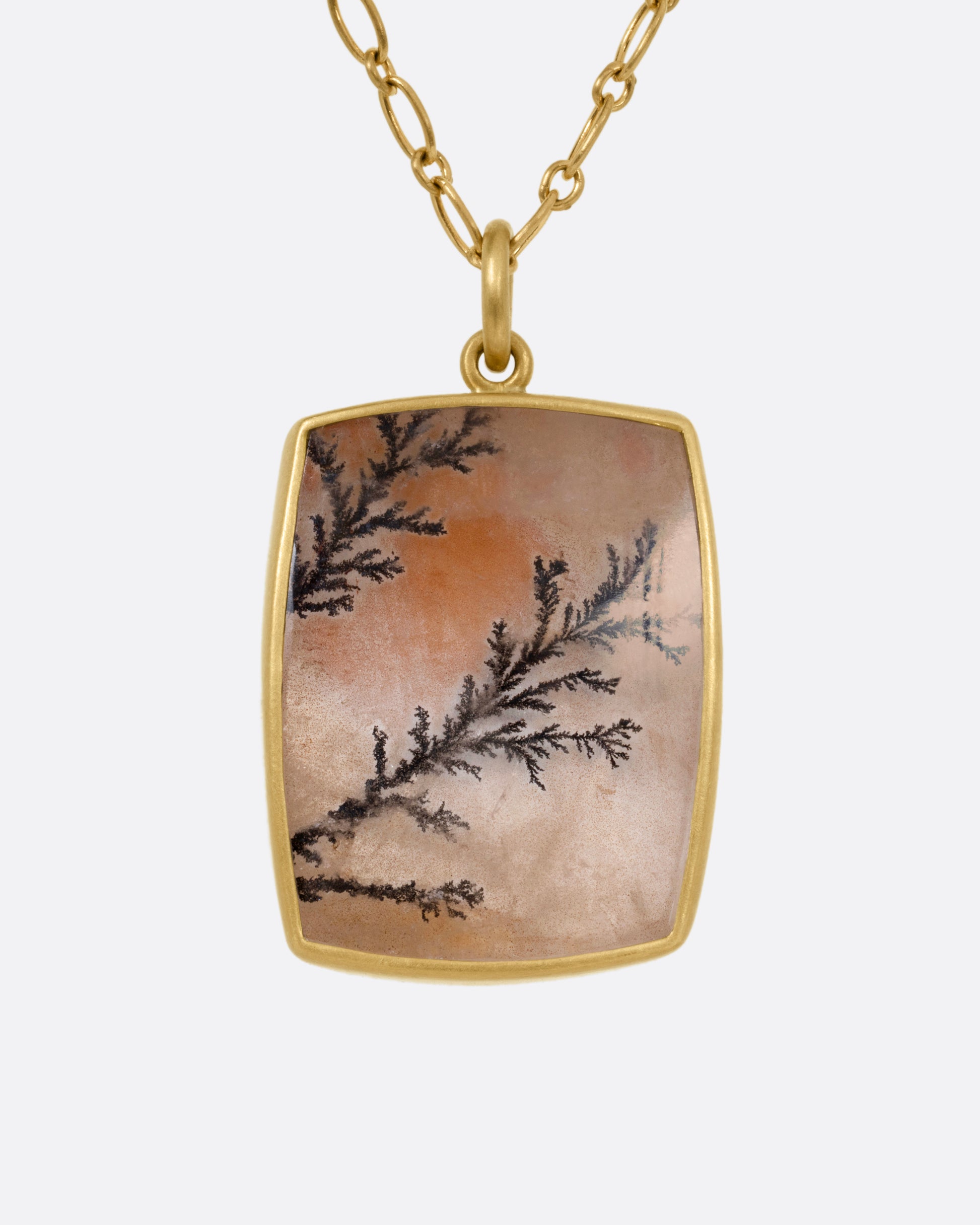 A yellow gold dendritic quartz pendant hanging from an alternating oval chain. Shown from the front.