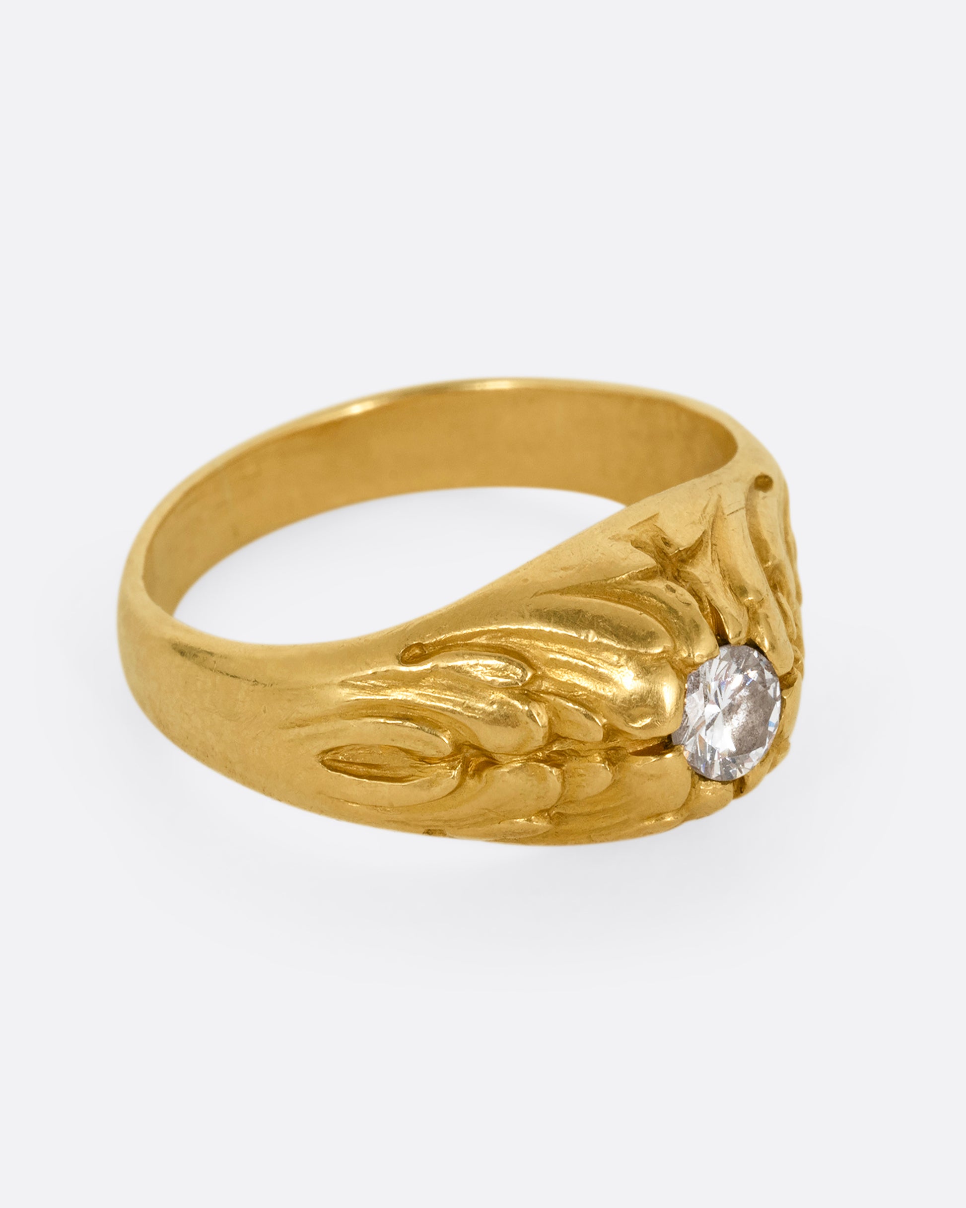 A yellow gold dome ring with  textural waves on its top and a round central diamond. Shown from the side.