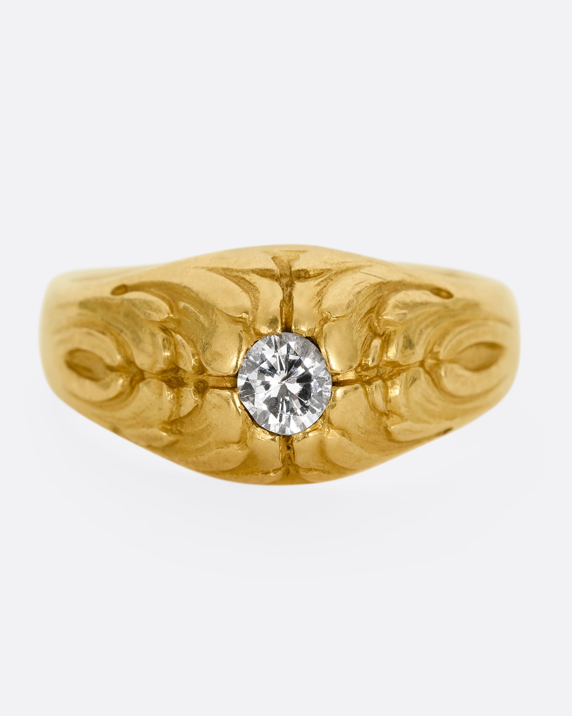 A yellow gold dome ring with  textural waves on its top and a round central diamond. Shown from the front.