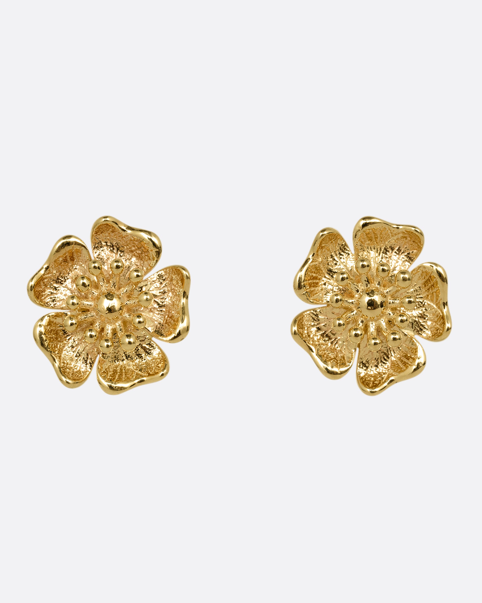 A pair of yellow gold flower stud earrings. Shown from the front.