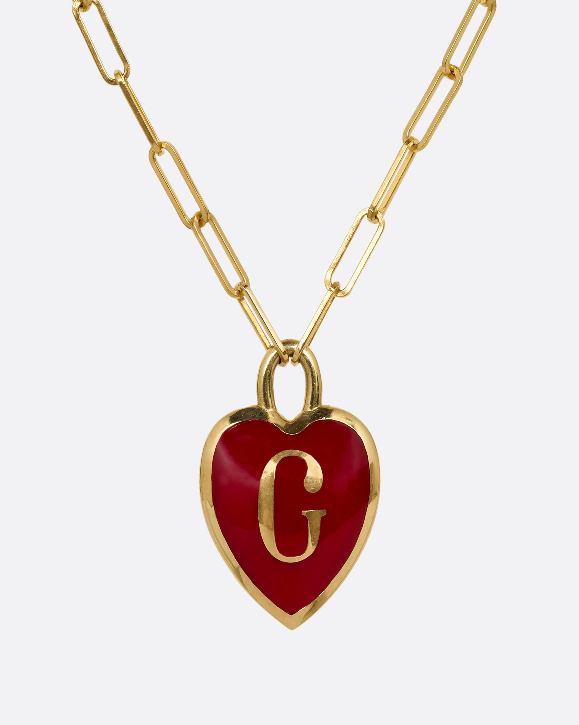 A yellow gold  paperclip chain necklace with a red enamel heart shaped G pendant. Shown from the front.