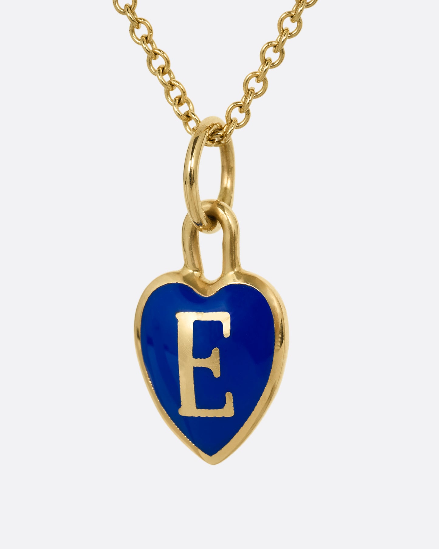 A yellow gold cable chain necklace with a blue enamel heart with a letter E at its center. Shown from the front.
