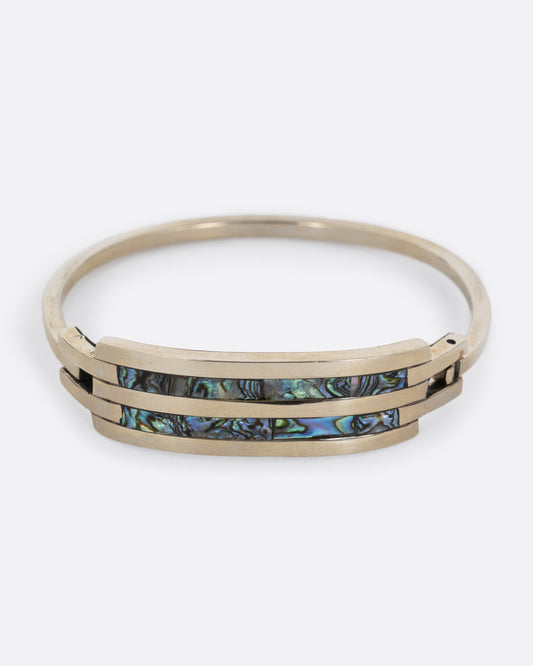 An alpaca silver bracelet with two abalone stripes and a hinged clasp. Shown from the front.