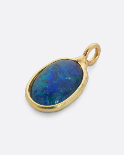 An Australian opal dangle set in yellow gold. Shown lying flat from the front.