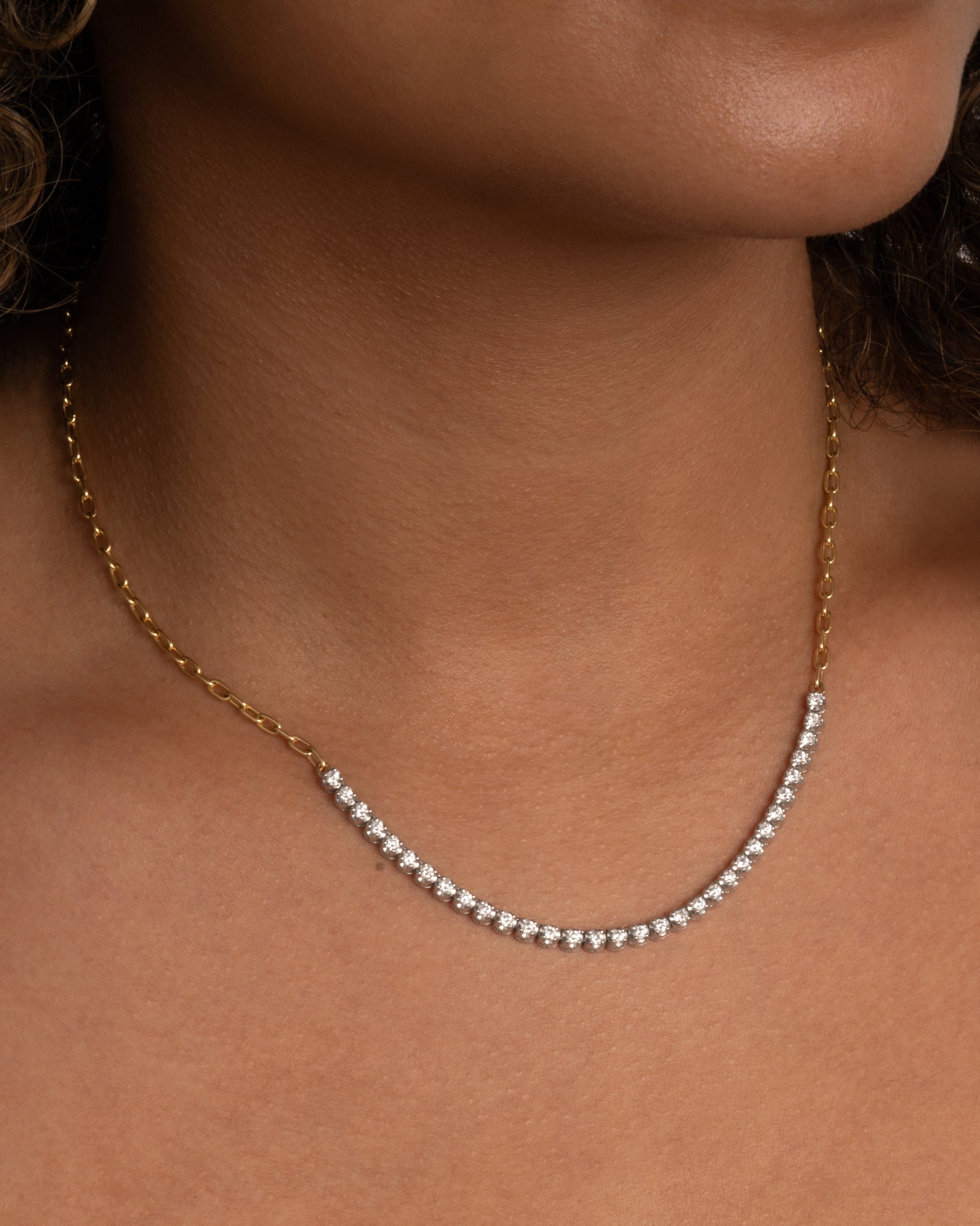 A yellow gold, oval link, chain necklace with four inches of contrasting white diamonds. Shown worn around the neck 