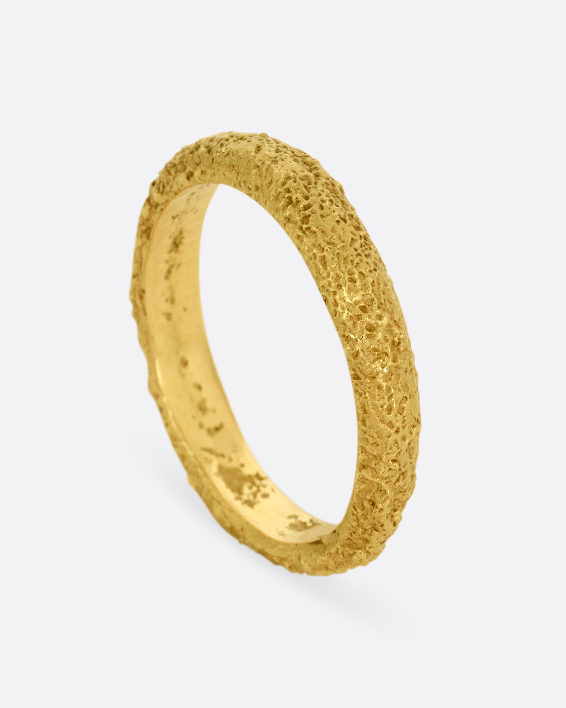 A textured yellow gold band. Shown standing up from the side.