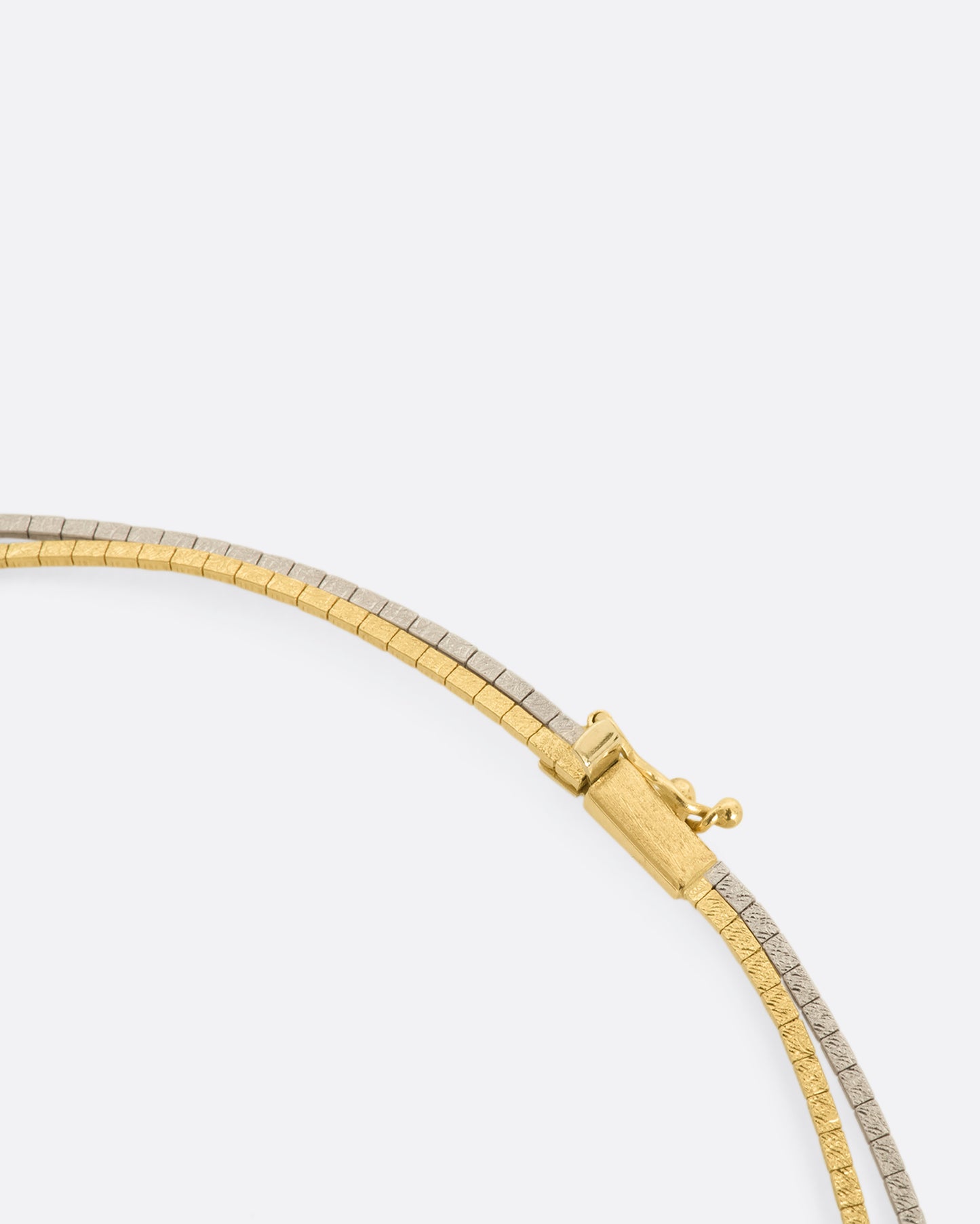 A two tone yellow and white gold double strand omega chain necklace. View of the clasp.