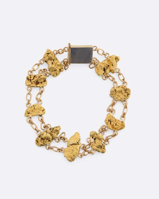 A yellow gold nugget bracelet featuring nine solid nuggets. View from above laying flat, closed.