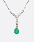 White gold necklace featuring diamonds and an emerald at the center. View close up from the front.