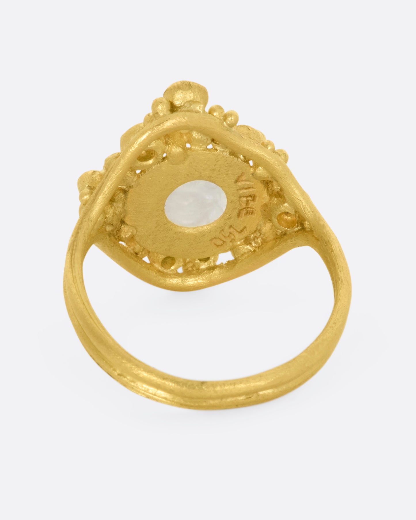 A yellow gold ring featuring a carved moonstone face with a halo of multicolored diamonds. View from the back.