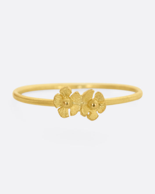 A ring with two yellow gold flowers on a dainty band. View from the front. 