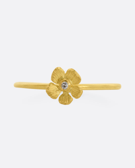 A small yellow gold flower with diamond at the center on a dainty band. View from the front.