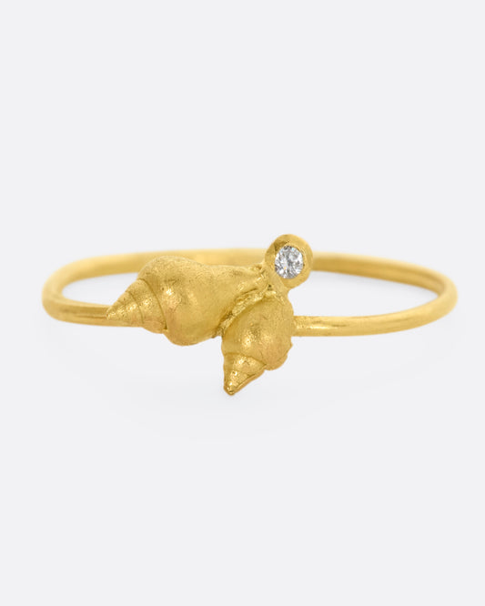 A ring with a cluster of two seashells and a diamond on a dainty band. View from the front. 