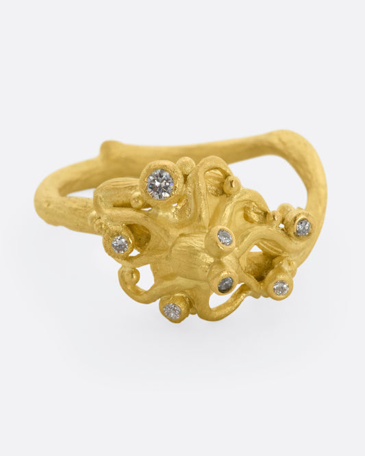 A yellow gold ring featuring an octopus with diamond eyes, surrounded by diamonds. View from the front.