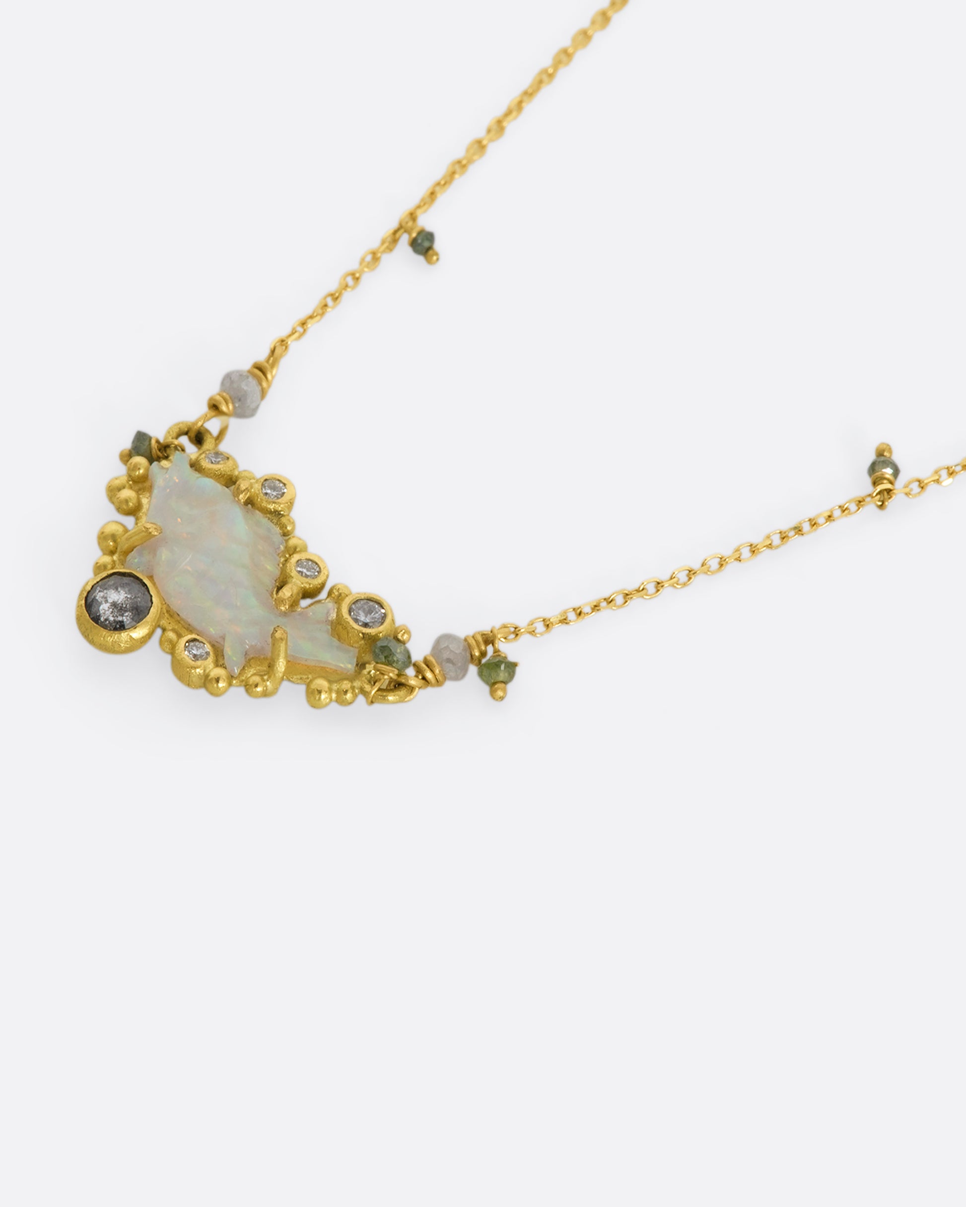 A yellow gold necklace featuring a carved opal fish surrounded by multicolor diamonds. View flat from the side.