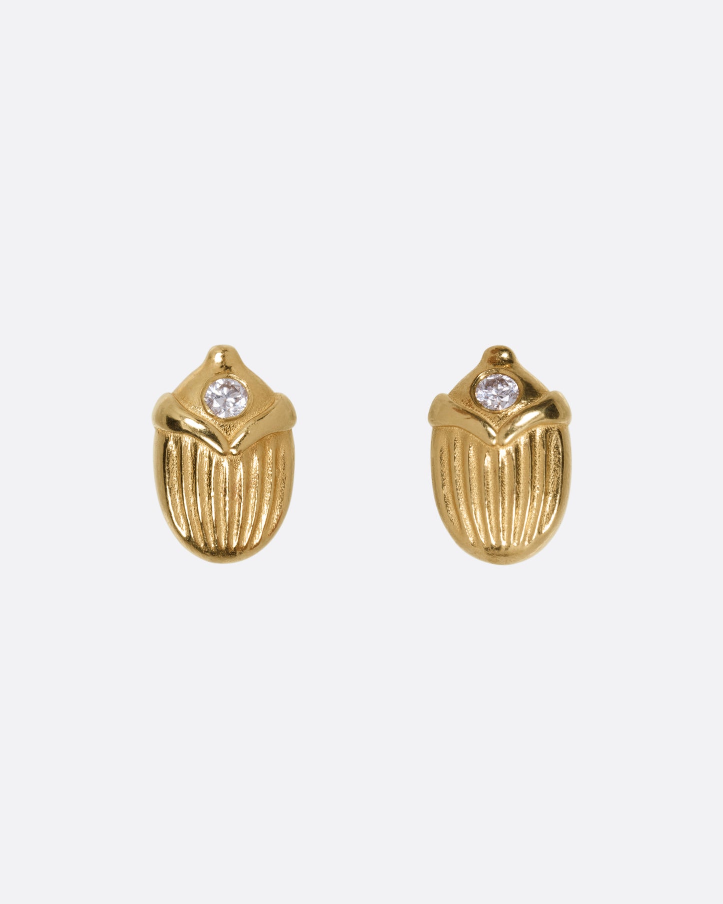 A pair of yellow gold scarab shaped stud earrings, each punctuated by a diamond, shown from the front.
