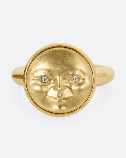 A yellow gold ring with a moon face and diamond eyes. Shown from the front.