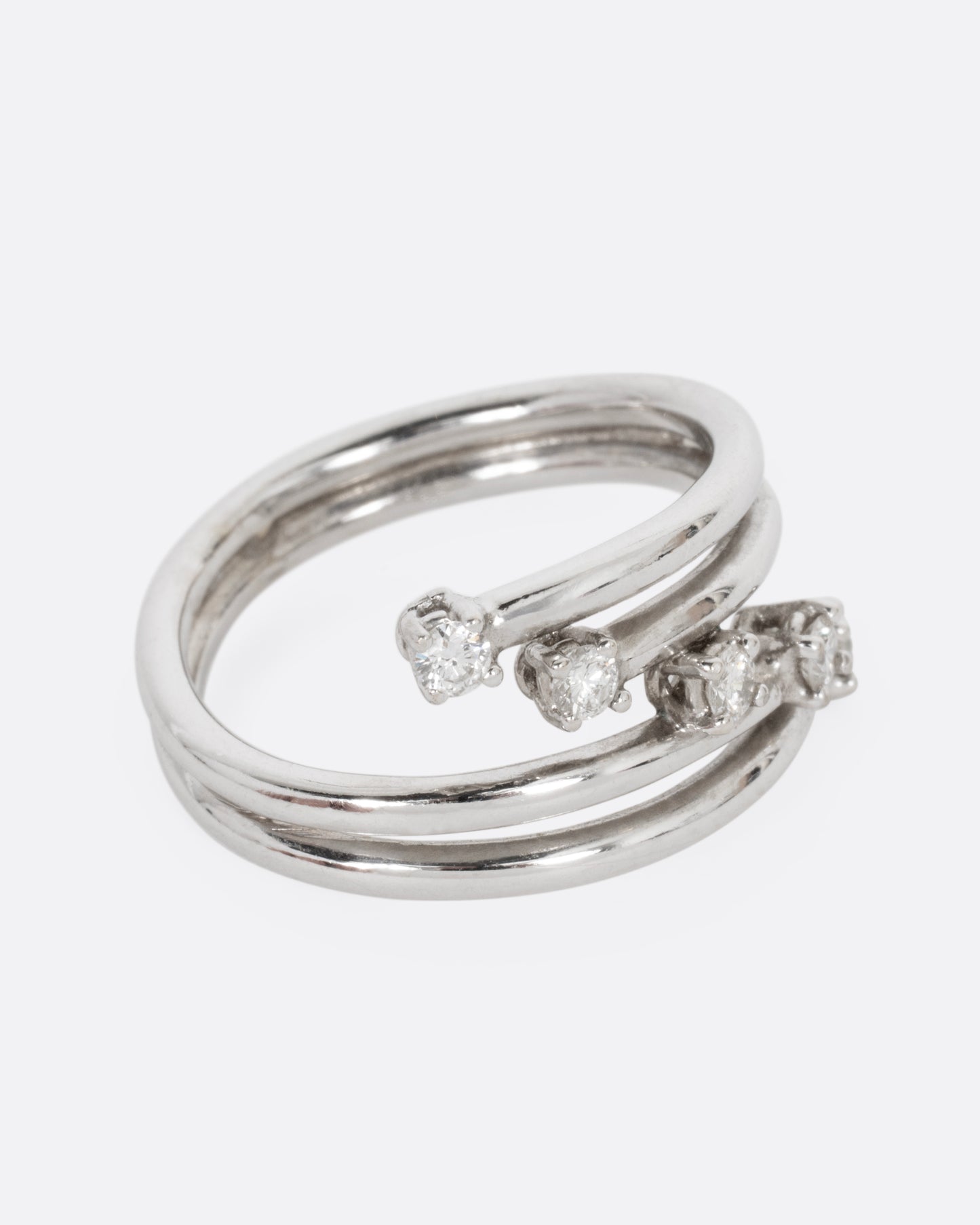 A white gold wrap ring with five diagonal prong set diamonds, shown from the side.