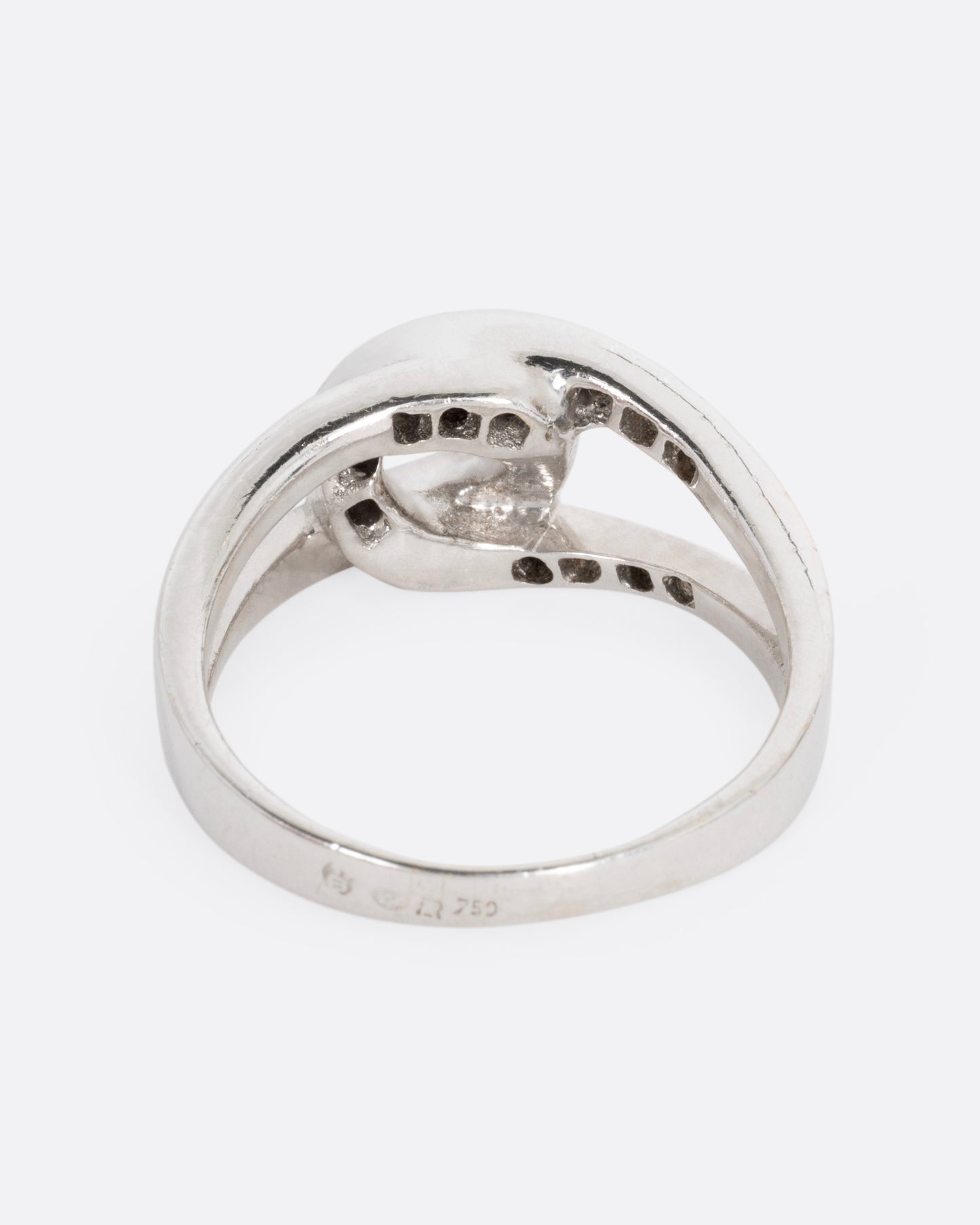A white gold ring with two interlocking loops; one studded with diamonds, shown from the back.