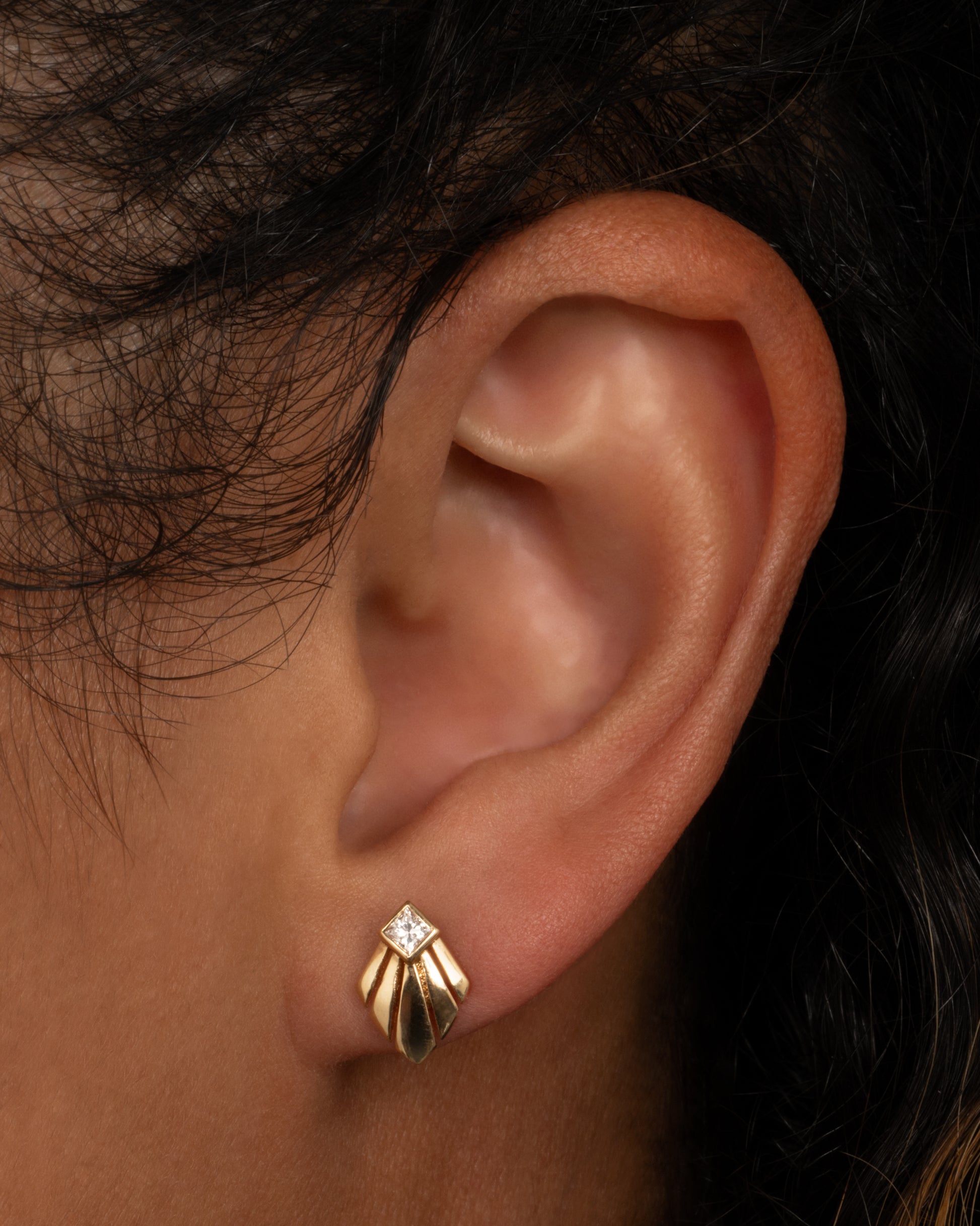 A 14k gold stud with a princess cut diamond—like a shooting star creating a trail of light across your ear. Shown worn in an ear.