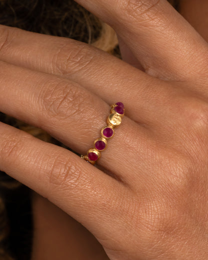 Anthony Lent Celestial band in yellow gold worn on a finger, round ruby cabochons in gold bezels with one carved moon face
