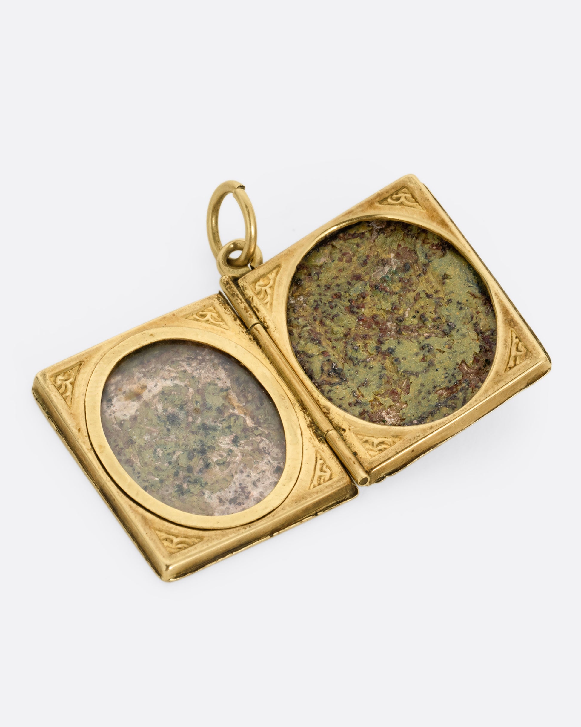 A yellow gold album locket with enamel detailing. Shown lying open from the front with two frames for photos; one with a protective cover. 