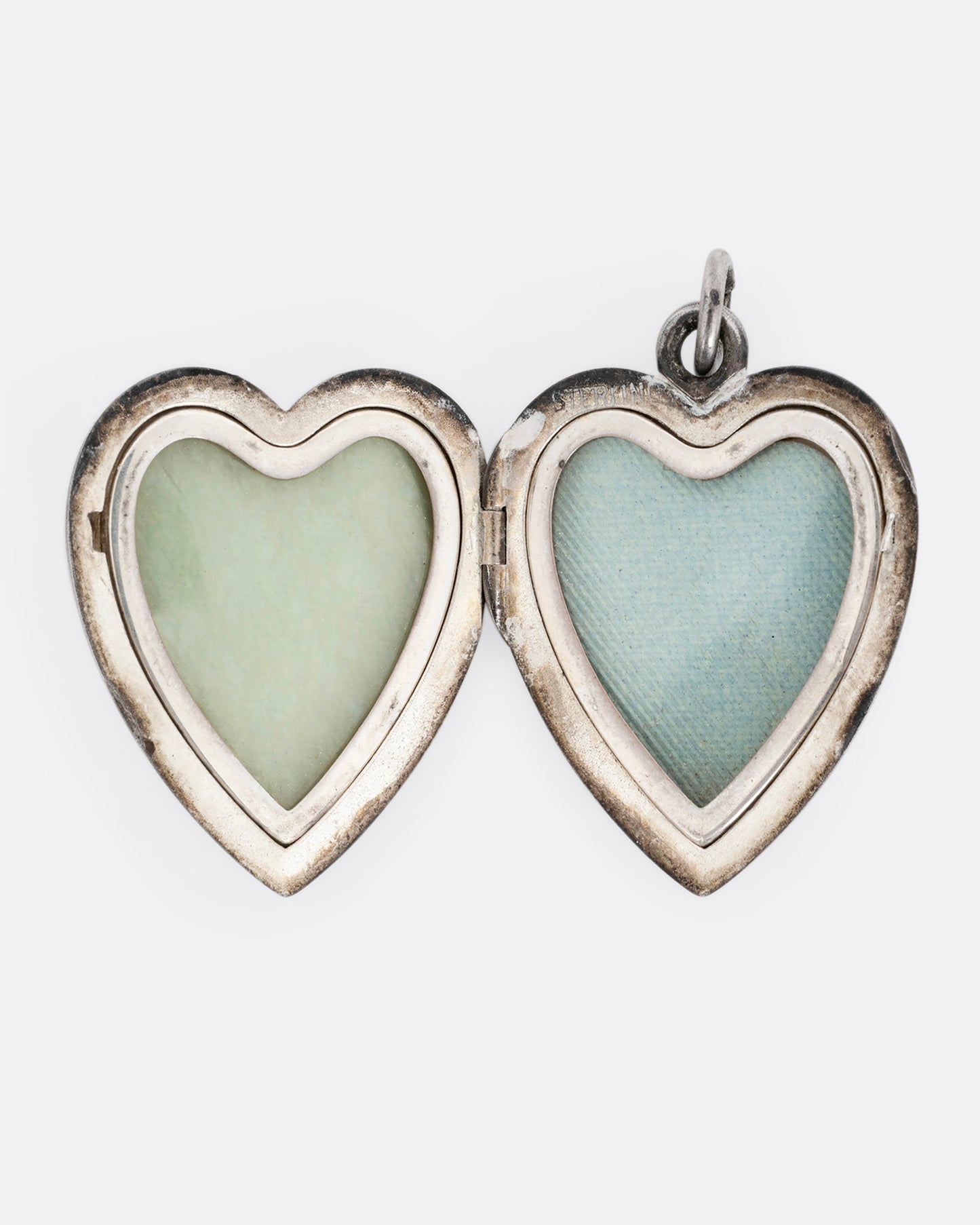 A silver heart shaped locket with two interior frames for photos. Shown open from the front.