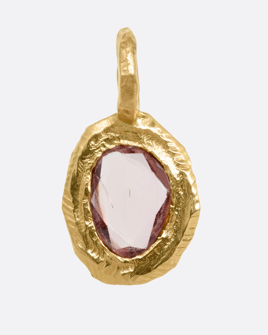 A yellow gold pendant with a burgundy sapphire, shown from the front