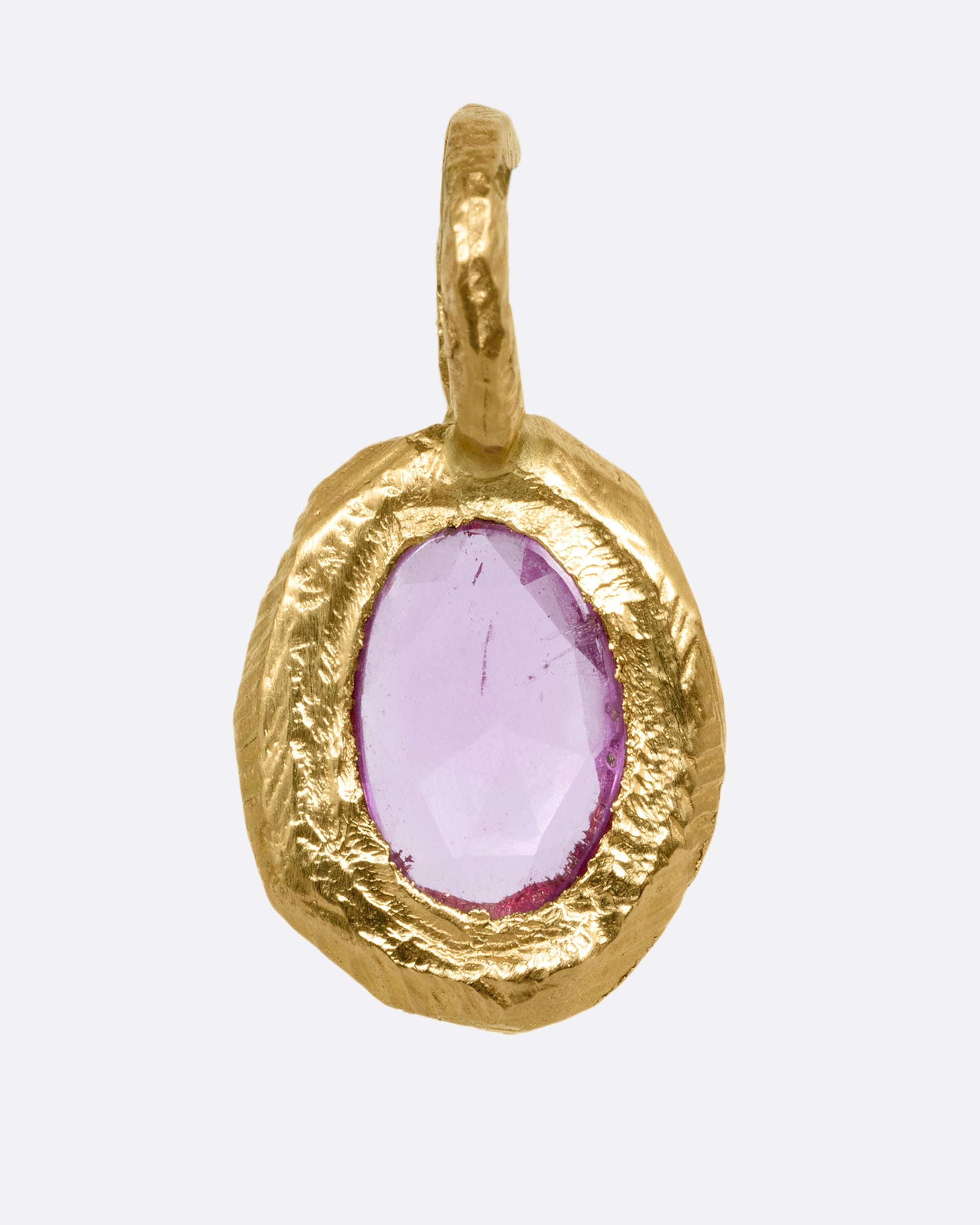 A yellow gold  pendant with a pink sapphire, shown from the front.