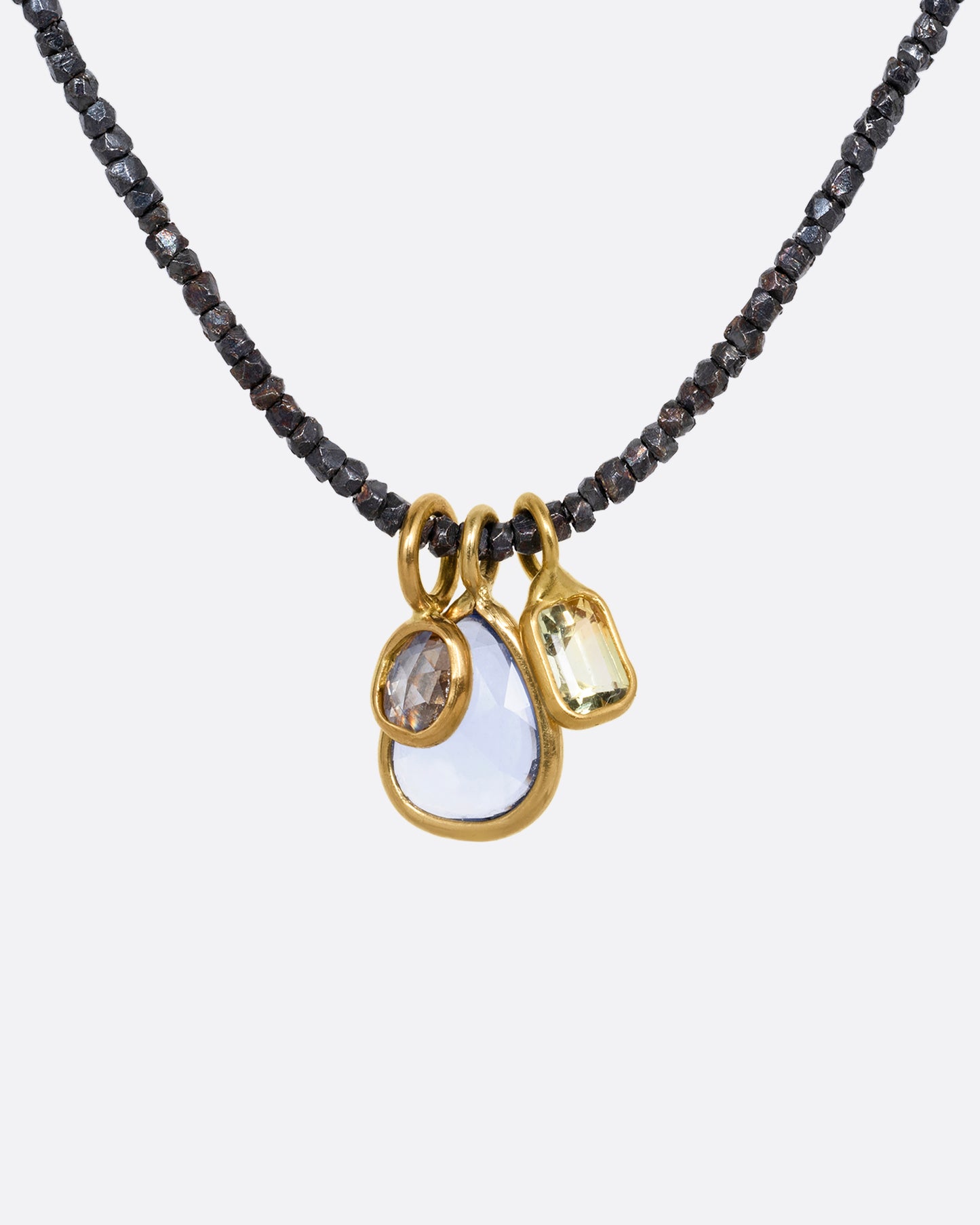 A necklace with oxidized silver Hill Tribe beads and a cluster of blue and green sapphires and a rose cut diamond. Shown from the front.