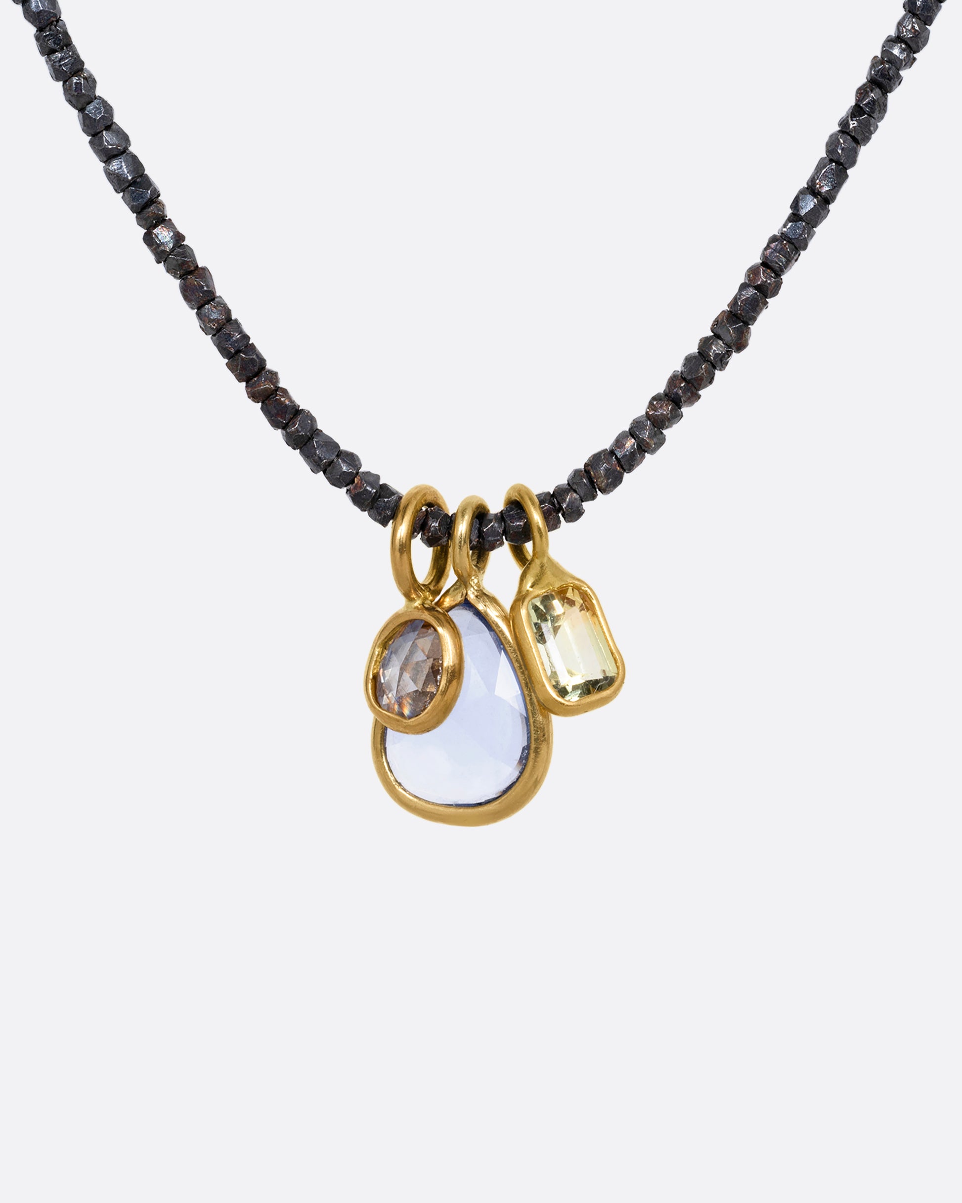 A necklace with oxidized silver Hill Tribe beads and a cluster of blue and green sapphires and a rose cut diamond. Shown from the front.