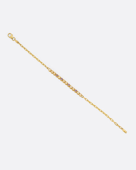 A yellow gold partial tennis bracelet with peach and yellow diamonds and purple sapphires. Shown from the front.