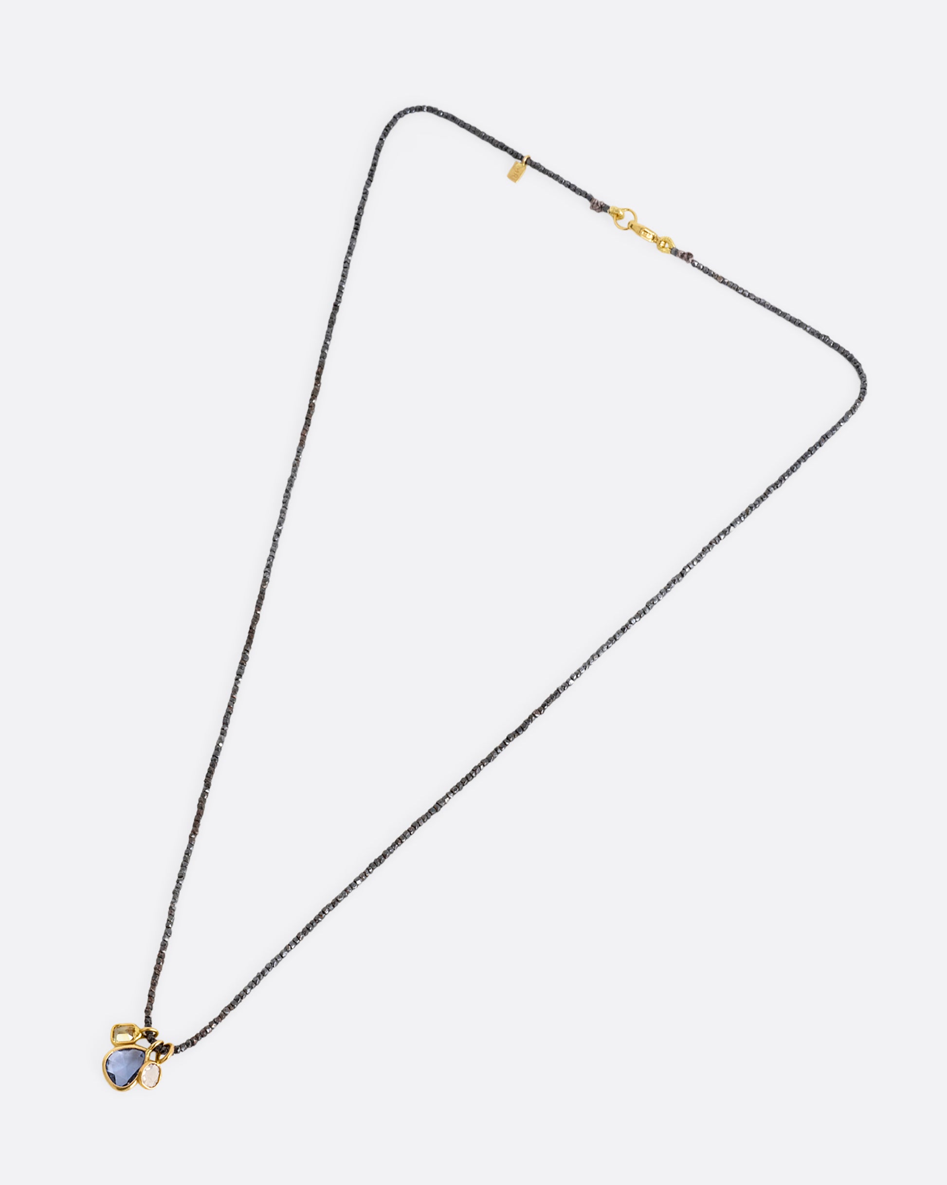 A necklace with oxidized silver Hill Tribe beads and a cluster of blue and green sapphires and a rose cut diamond. Shown lying flat from the front.