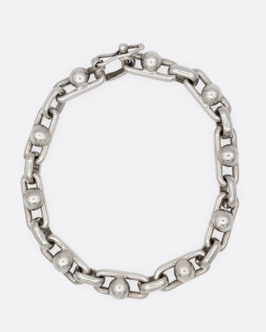 A silver bracelet with spheres at the center of each link. Shown from the front.