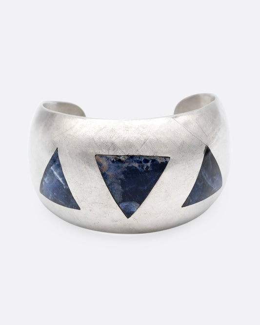 A broad silver cuff with three large lapis triangles along its convex front. Shown from the front.