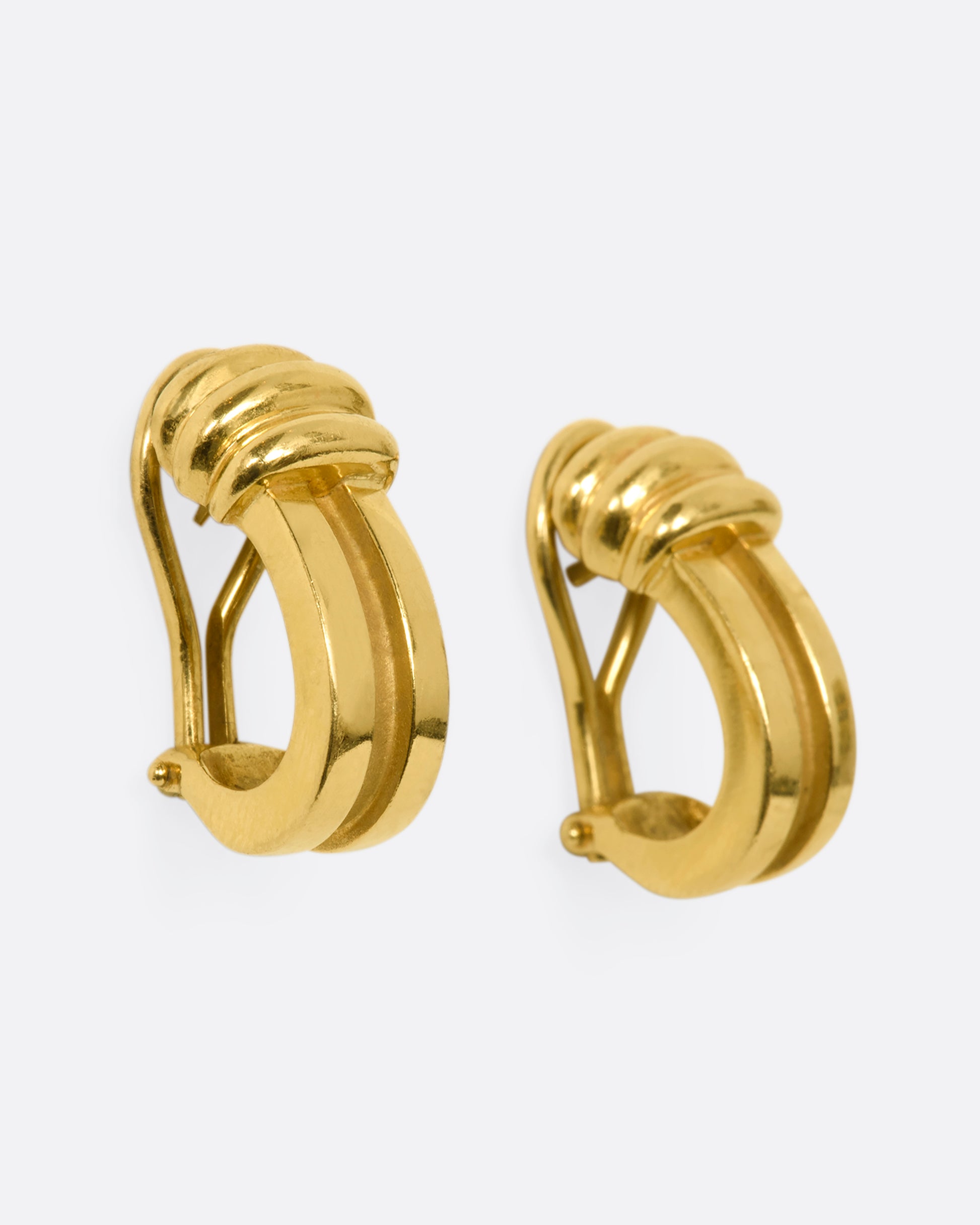 Yellow gold J-shaped earrings with omega backings. View from the side.