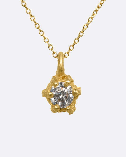 Yellow gold necklace with solitaire diamond in a textured prong setting. View close up from the front.