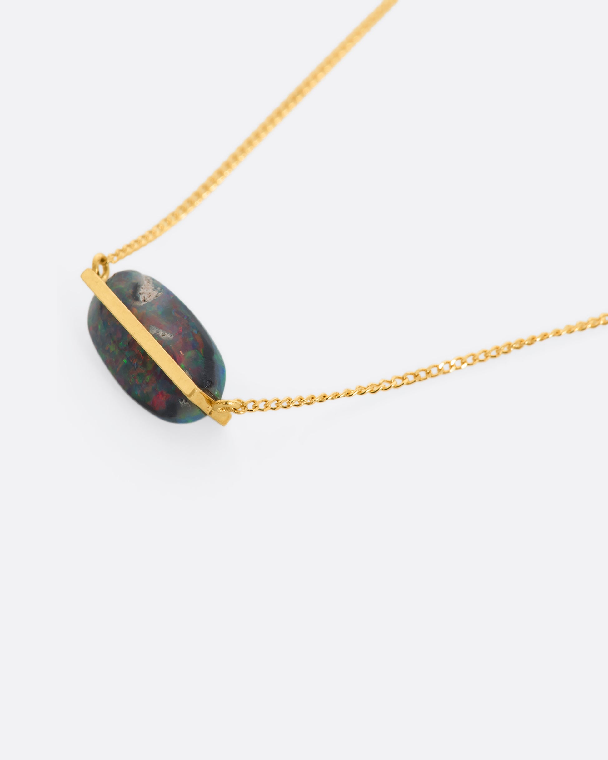 A yellow gold necklace with an oval black opal. View up close of the back from the front.