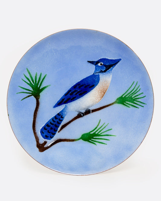 An enamel dish with a blue jay sitting on a branch, shown from the top.