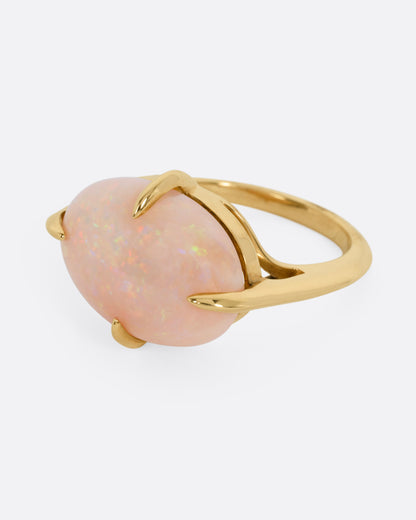 A yellow gold ring with a prong set opal, shown from the side.