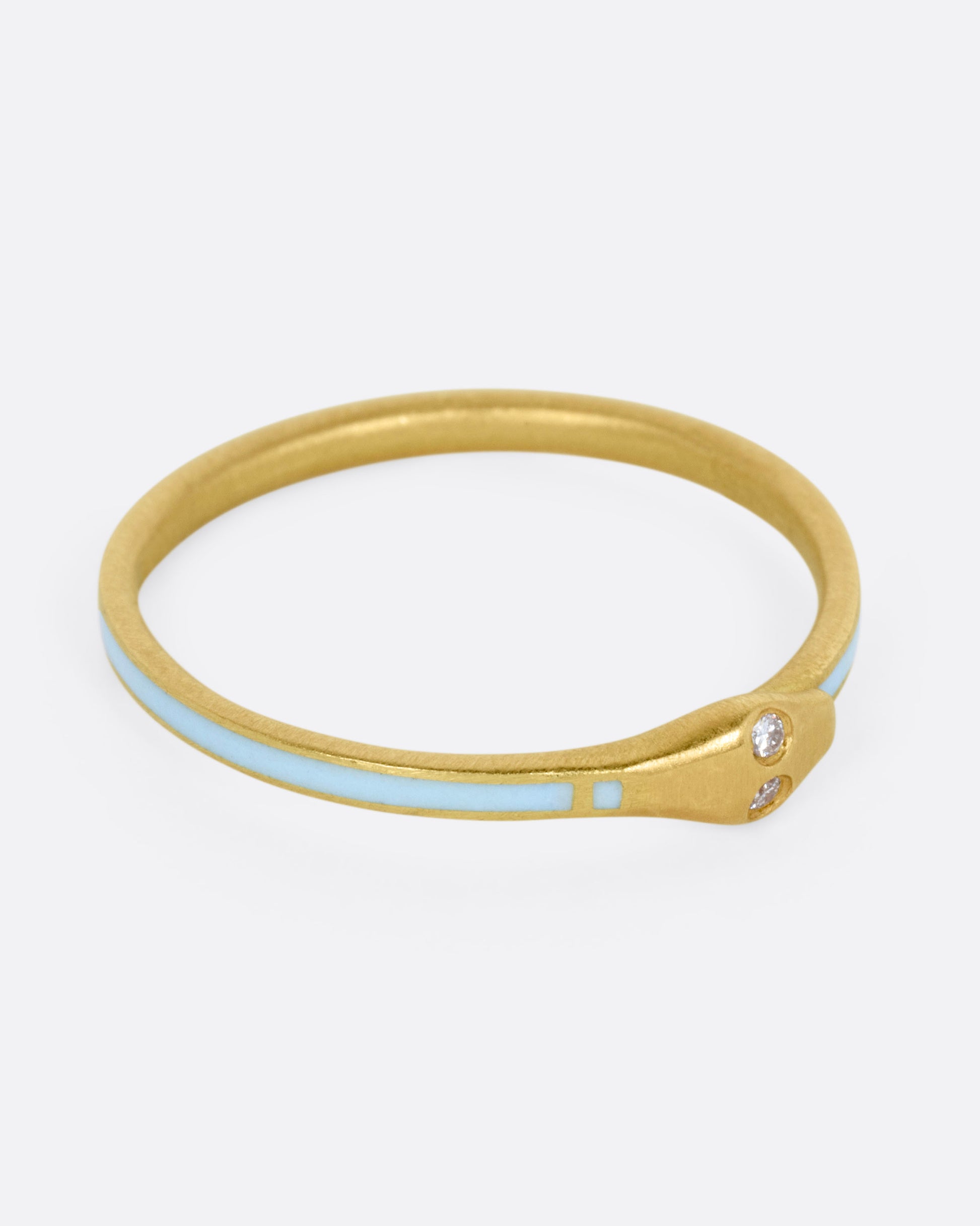 A yellow gold ouroboros ring with diamond eyes and light blue enamel, shown from the side.