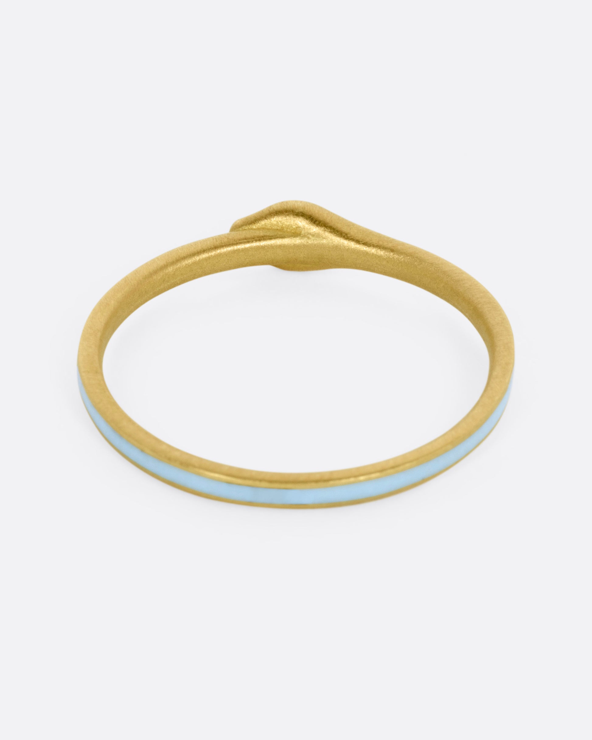 A yellow gold ouroboros ring with diamond eyes and light blue enamel, shown from the back.