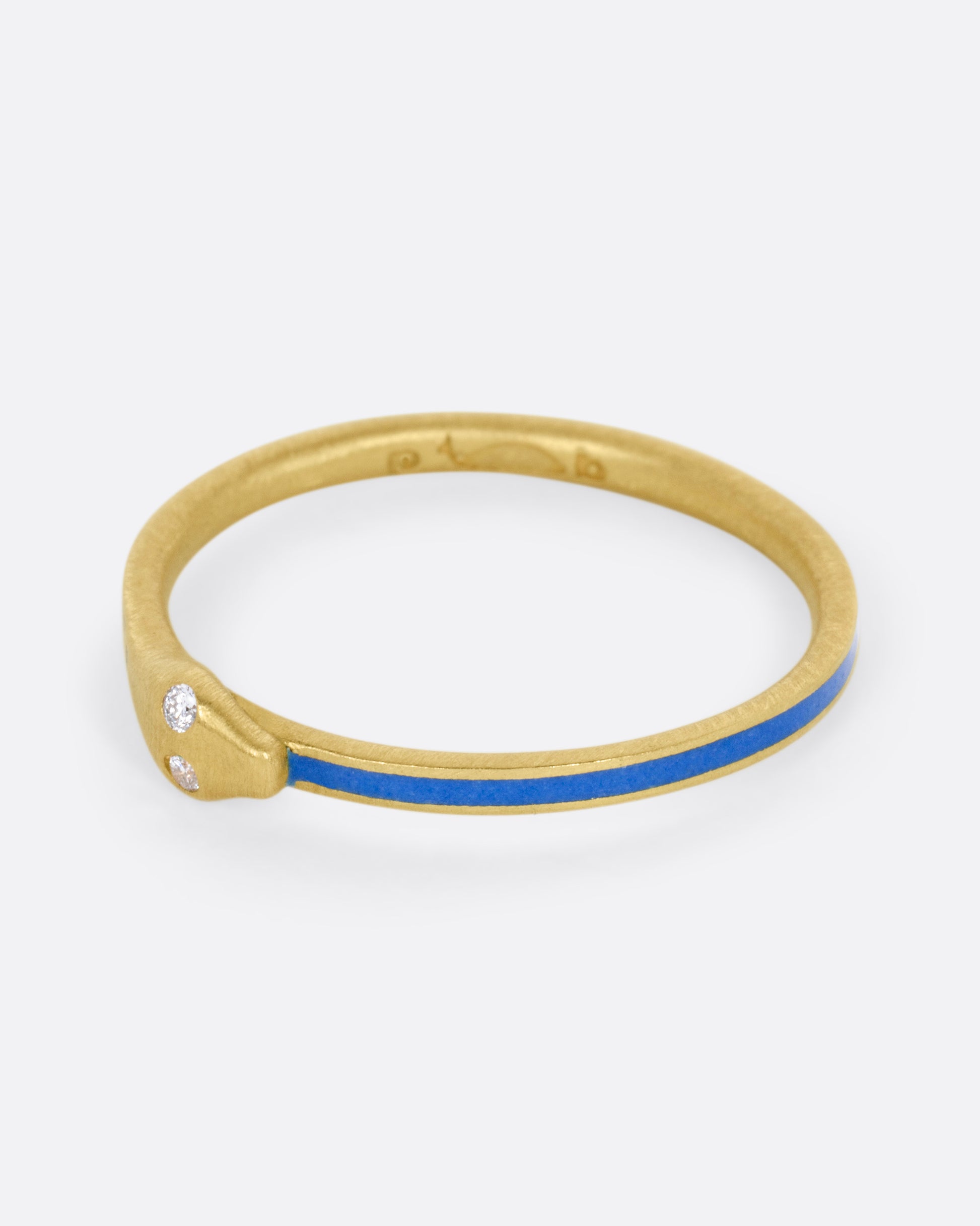 A yellow gold ouroboros ring with diamond eyes and blue enamel, shown from the side.