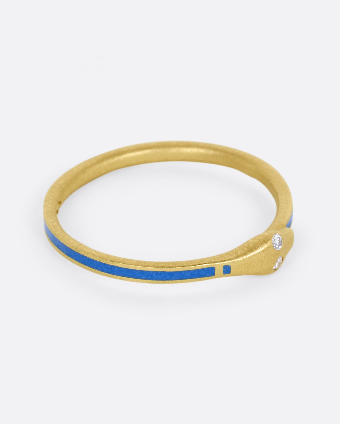 A yellow gold ouroboros ring with diamond eyes and blue enamel, shown from the side.